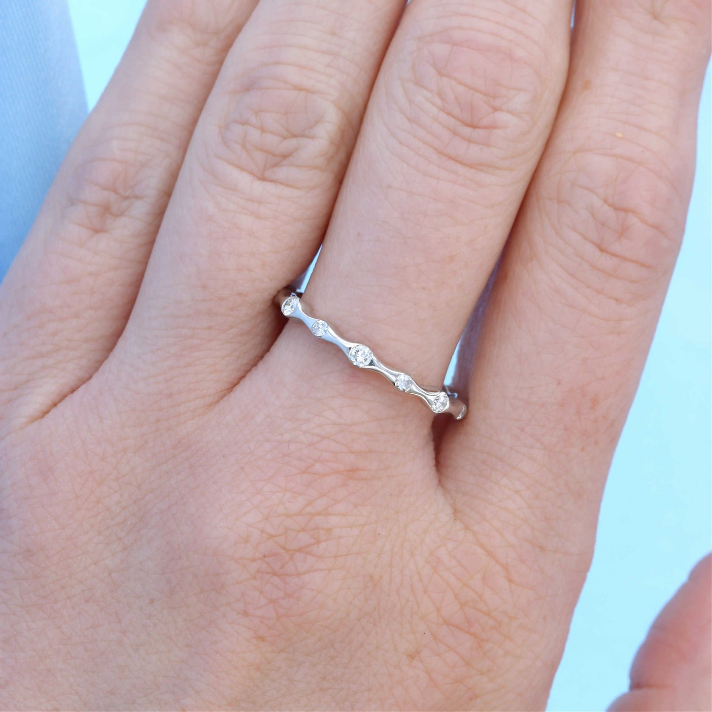 Dainty Scalloped Diamond Eternity Wedding Band on a Finger